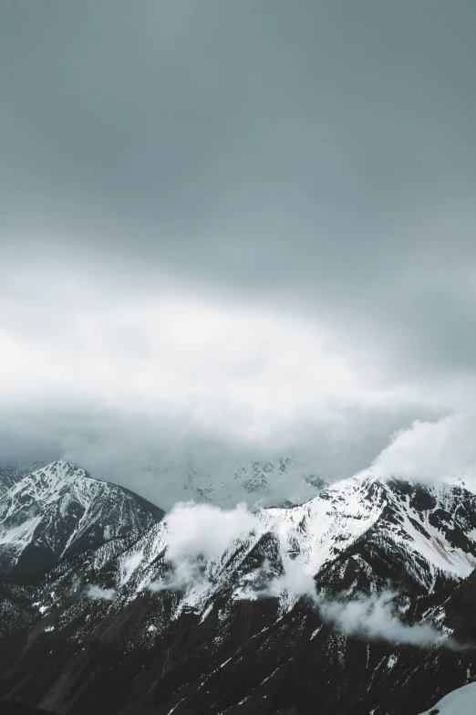 the snowy mountains are covered in clouds on an overcast day