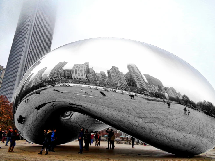 large silver sculpture in front of a city skyline