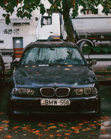 a black bmw car is parked next to a tree and bench
