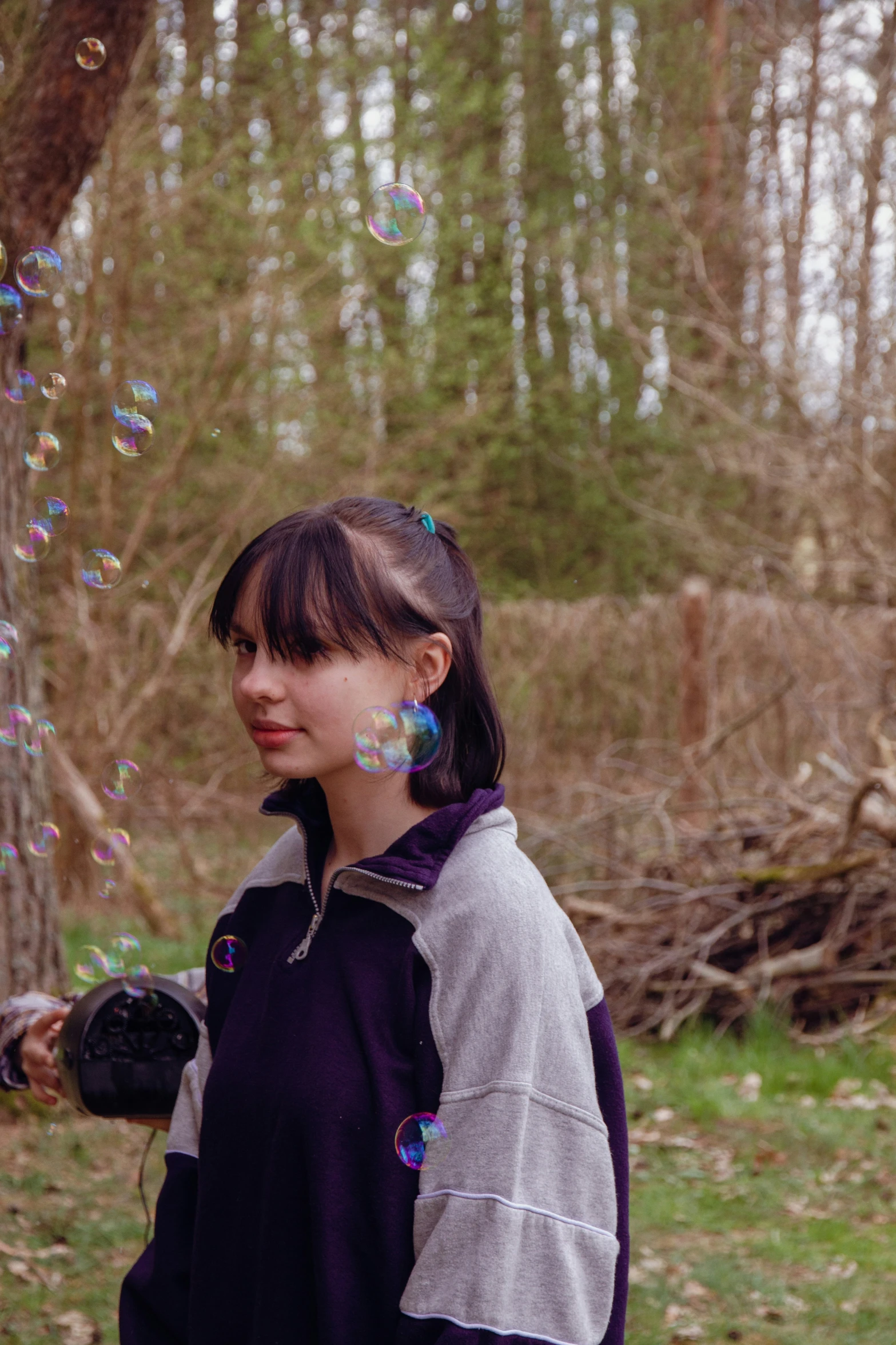 girl in a purple coat blowing bubbles off