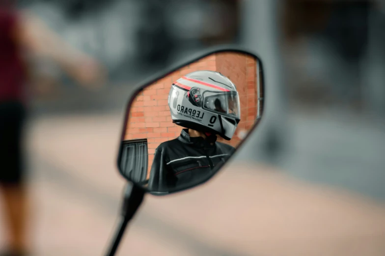 someone's helmet sits in the side view mirror of their motorcycle