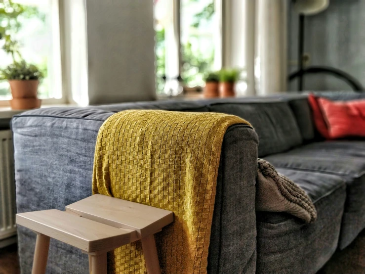 a living room with a couch and chair, and a wooden foot stool