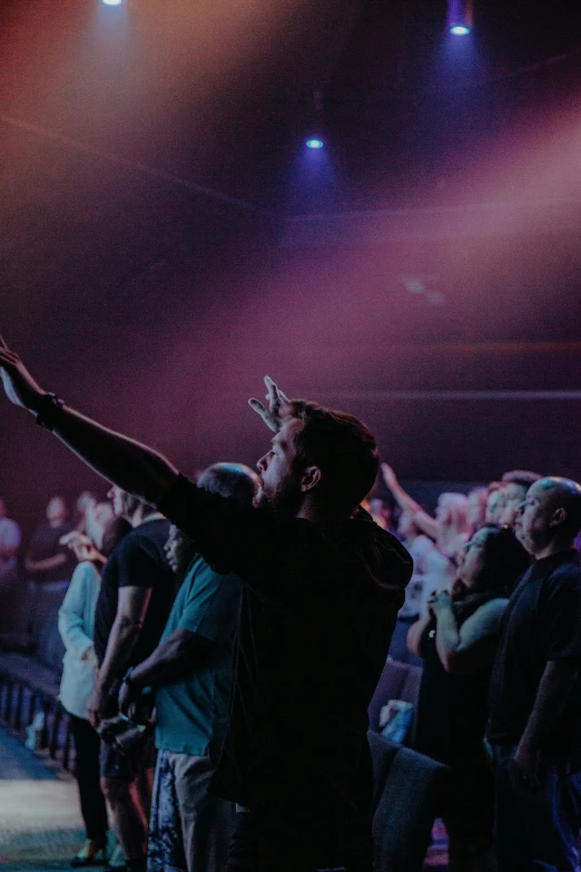 a crowd is dancing at a concert and the man has one arm up