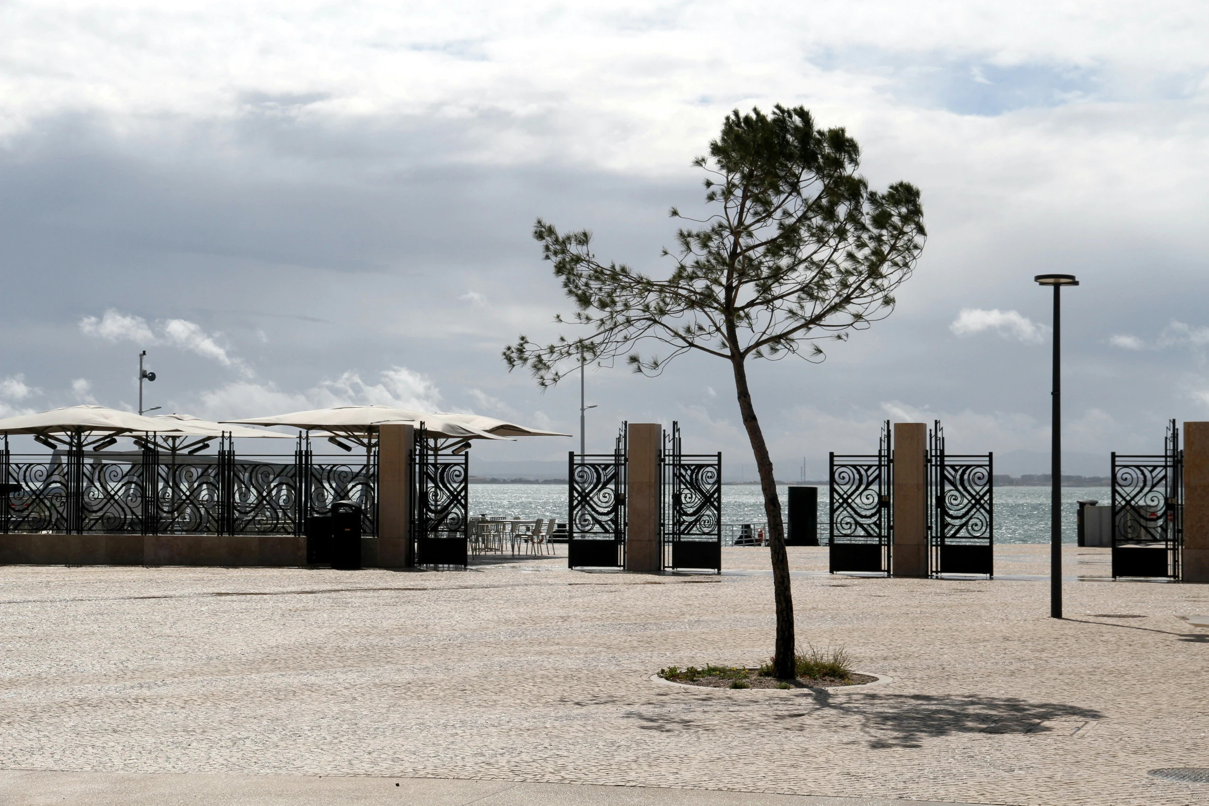 an empty park next to the beach with umbrellas on it