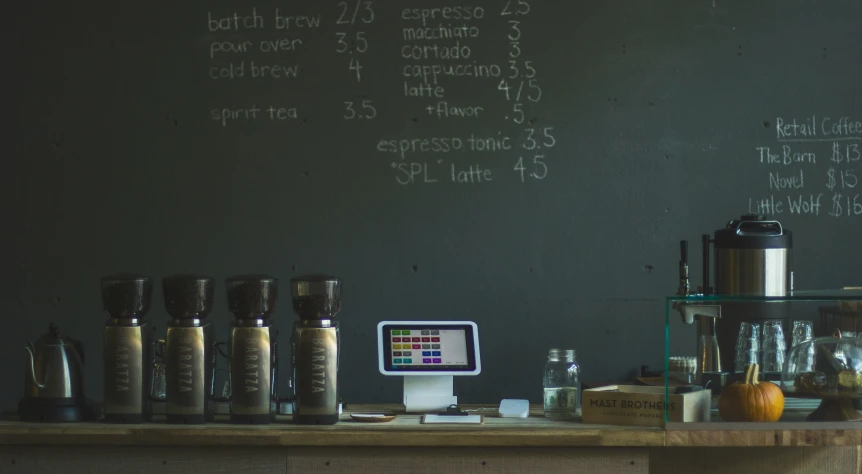 a coffee maker on a wooden counter in front of a blackboard