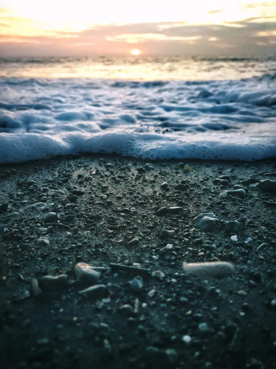 a small beach with waves coming in and a lone white bird is on the shore