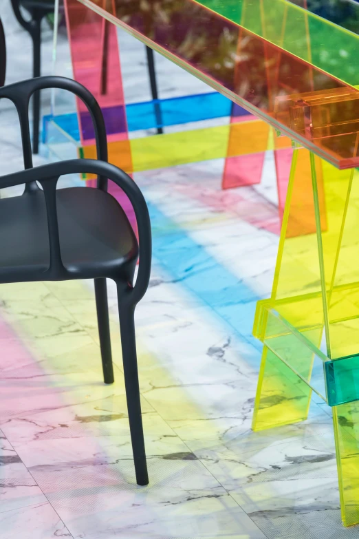 some black chairs a rainbow colored table and an interesting bench