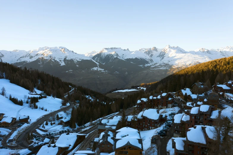 snow covered mountains and buildings line the side of a mountain