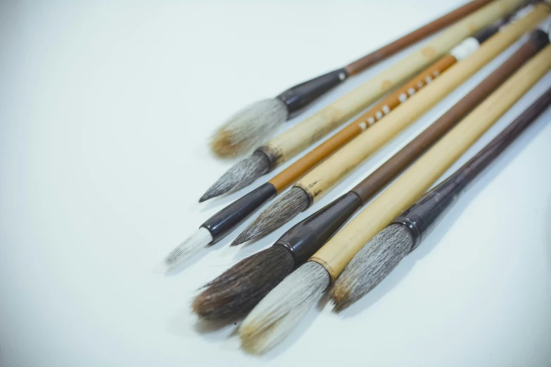 five paint brushes are lined up and the one on the left has multiple pointy heads