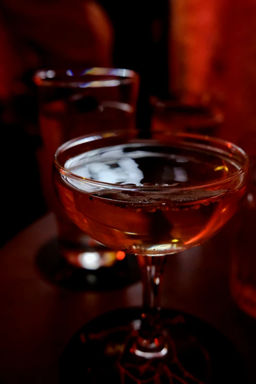 two glasses filled with drinks sit on a table