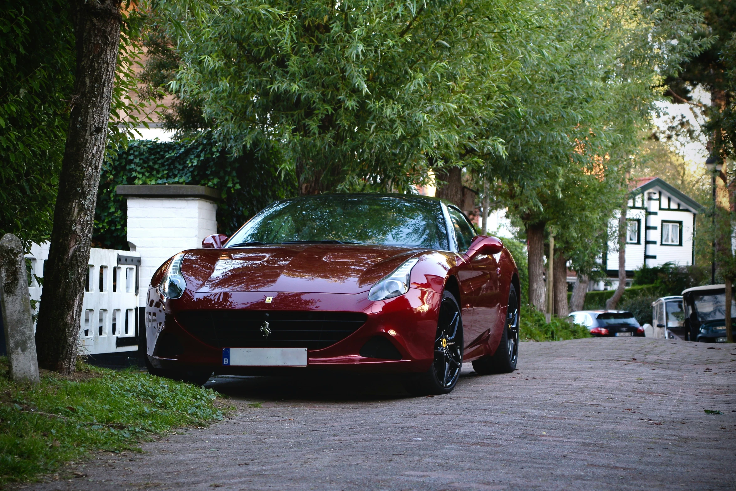 this is a red car in the road next to trees