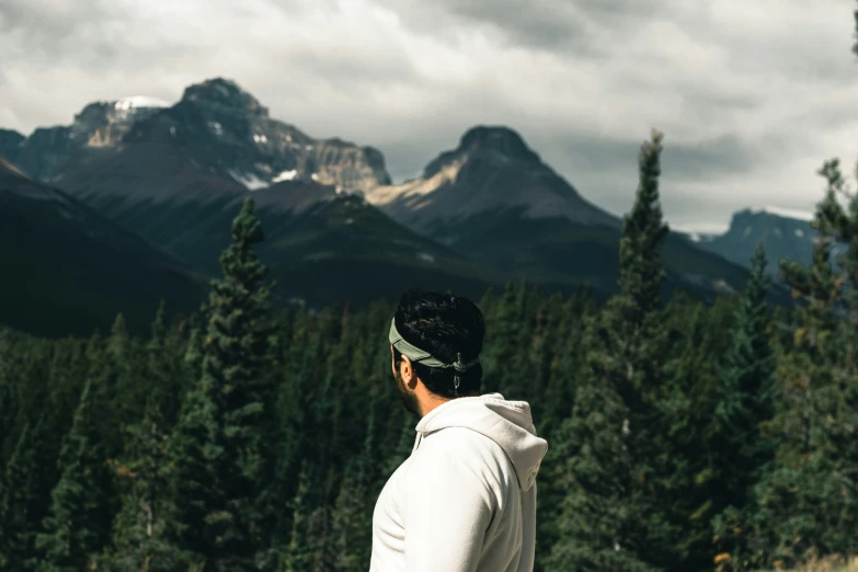 a man standing in a forest looking at the mountains