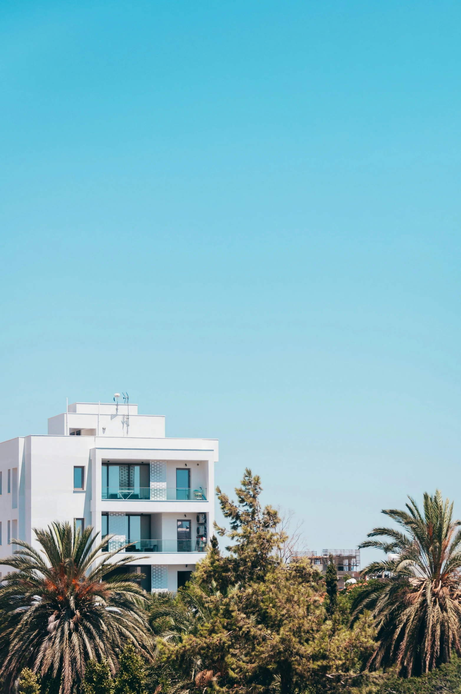 a building stands on the side of trees with blue sky in the background