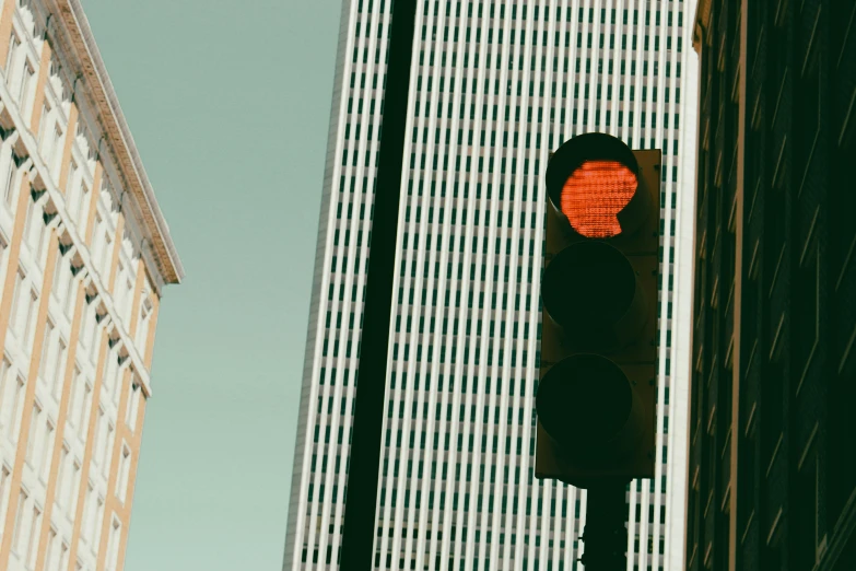 a red traffic light near two tall buildings