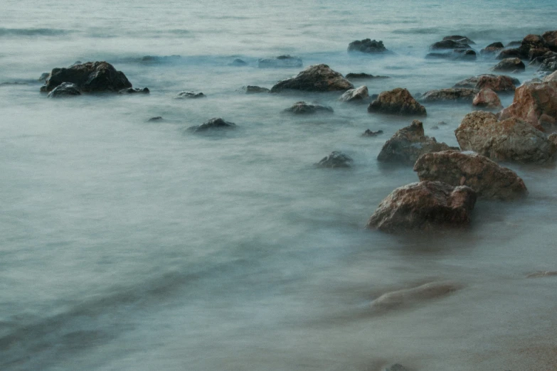 waves are breaking up on the shore with rocks