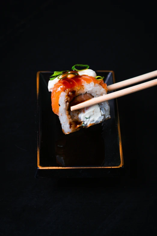 a black surface with a small dish of sushi