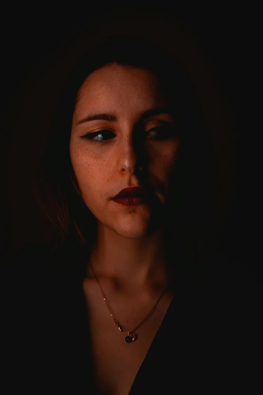 a woman with a necklace stares at the camera