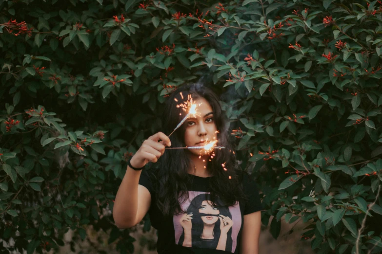 a woman with a sparklestick that is standing in front of a tree