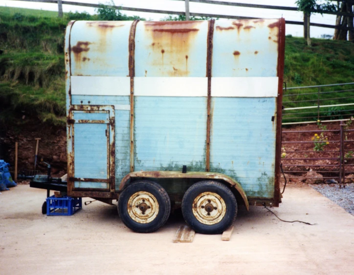 the old tractor trailer is parked outside in a dirt lot