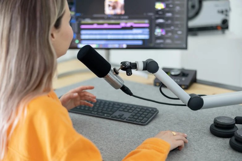 young lady in orange shirt recording an article on a computer