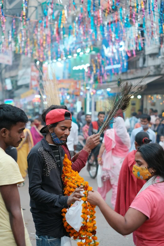 two people in colorful outfits hanging decorations around a city street