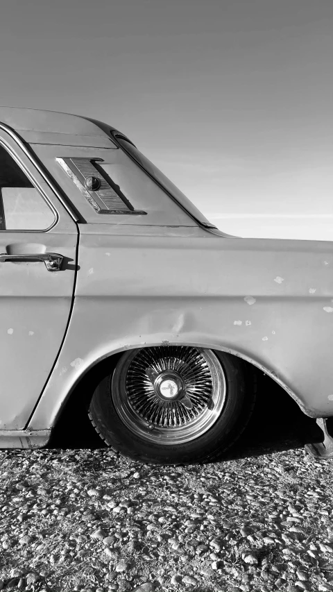 an old grey car sitting on the side of the road