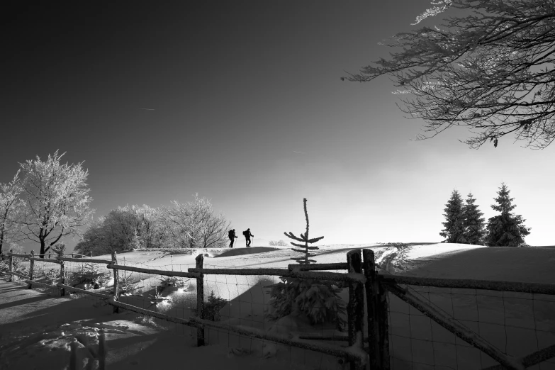 a lone person in the snow near a fence