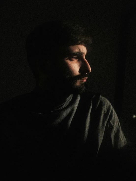 a man standing in the dark looking away from the camera