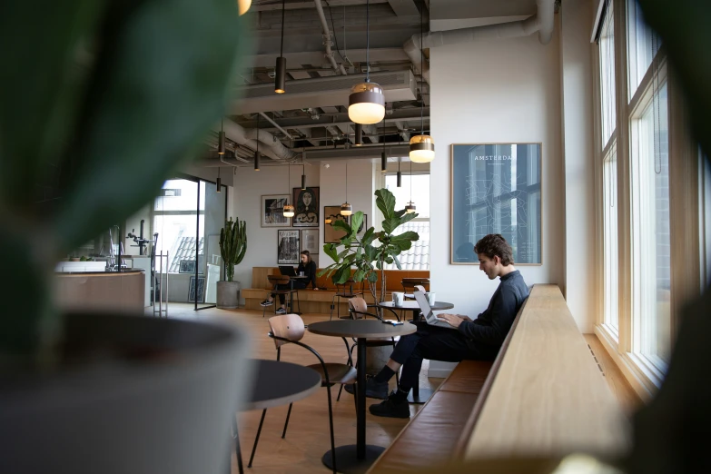 man sitting on bench in a restaurant near large window