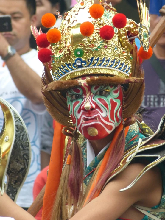 a person with colorful make up, wearing a crown and posing