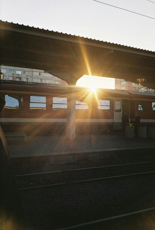 a subway is parked under a bridge at sunset