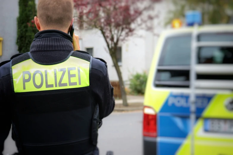 a police officer on the phone near an emergency vehicle