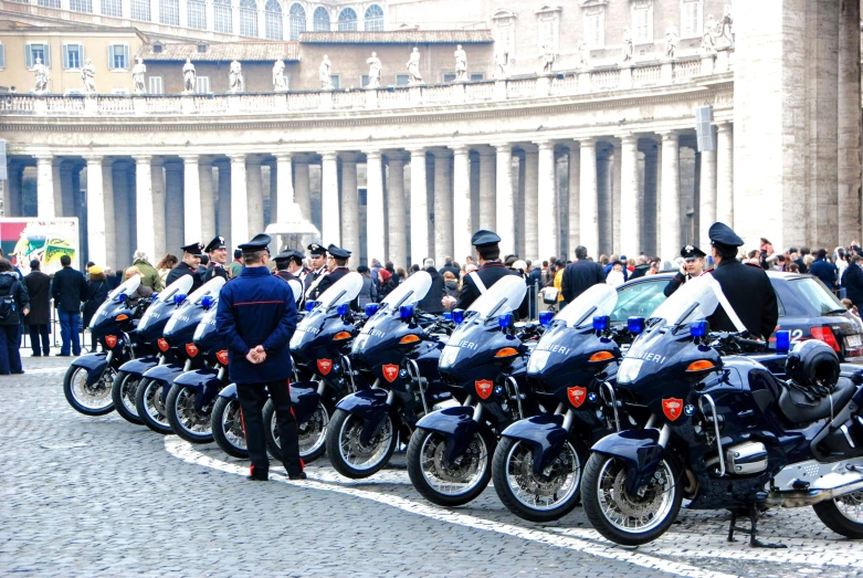 police officers stand beside motorcycles in front of a crowd