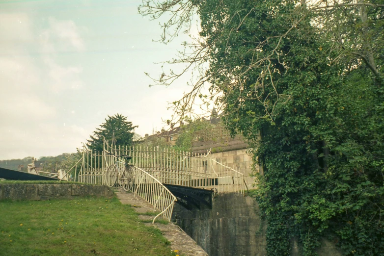 a bridge with stairs and gates that lead up to a small grassy area