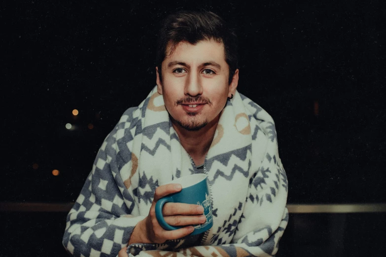 a man in a patterned sweater holding a mug