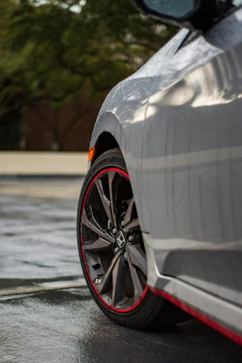 the front wheels of a gray sport car on a wet road
