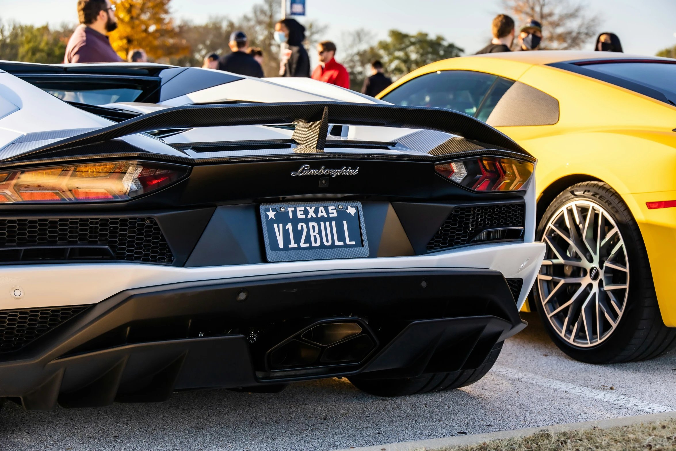 two sports cars side by side with people standing around