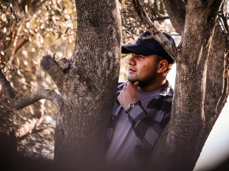 a man standing behind a tree in front of some nches