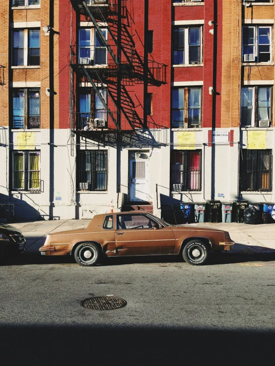 an old car sits parked in front of the city block