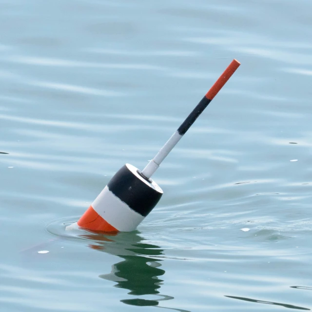 an orange and white cone floating in the water