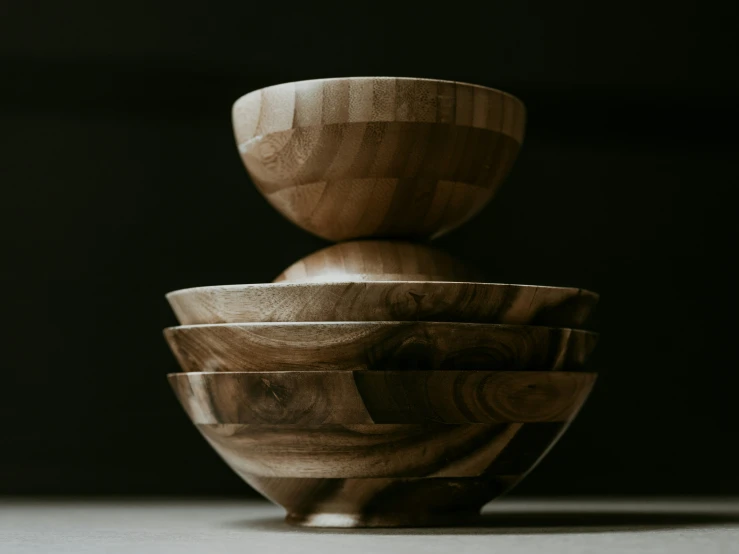 the stack of wooden bowls is sitting on the surface
