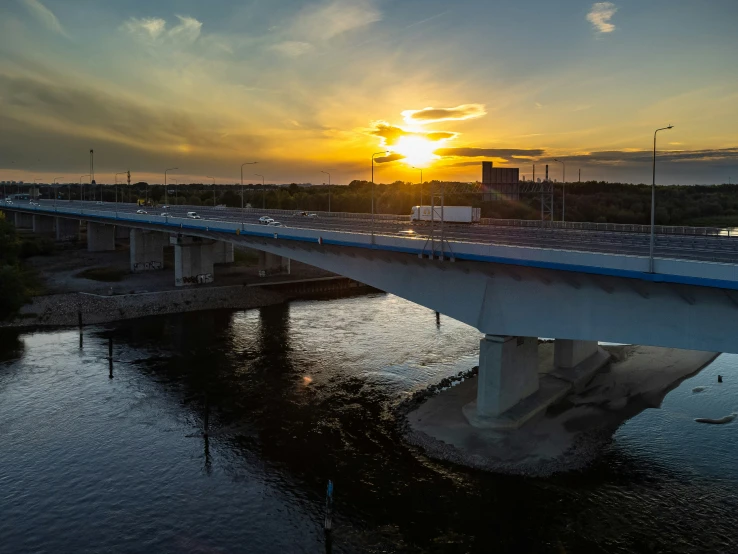 the sun is setting over a highway bridge