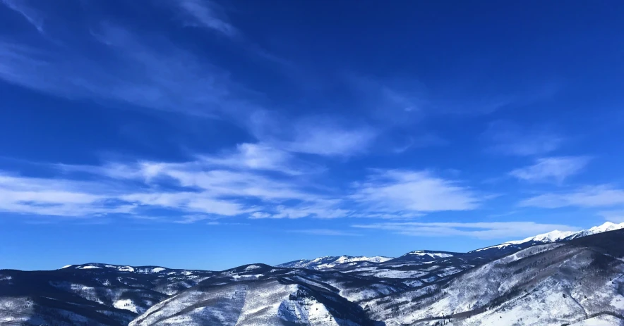 a snowy slope in the middle of a mountain under a blue sky