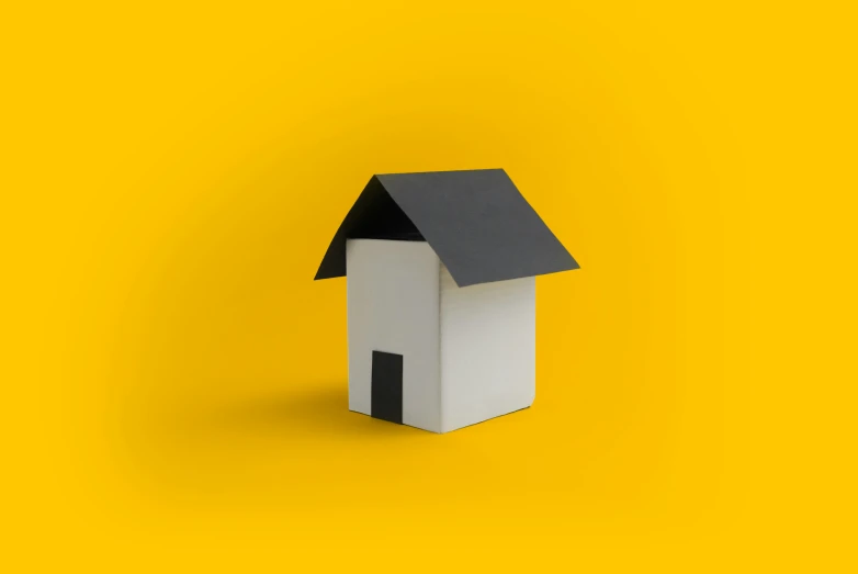 an empty house is standing upright on a yellow surface