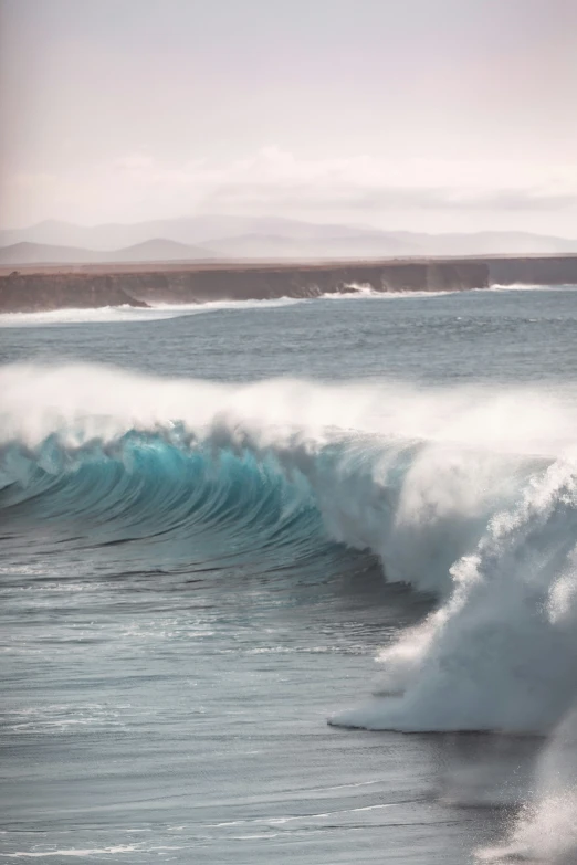 a large wave breaking over the ocean while people look on