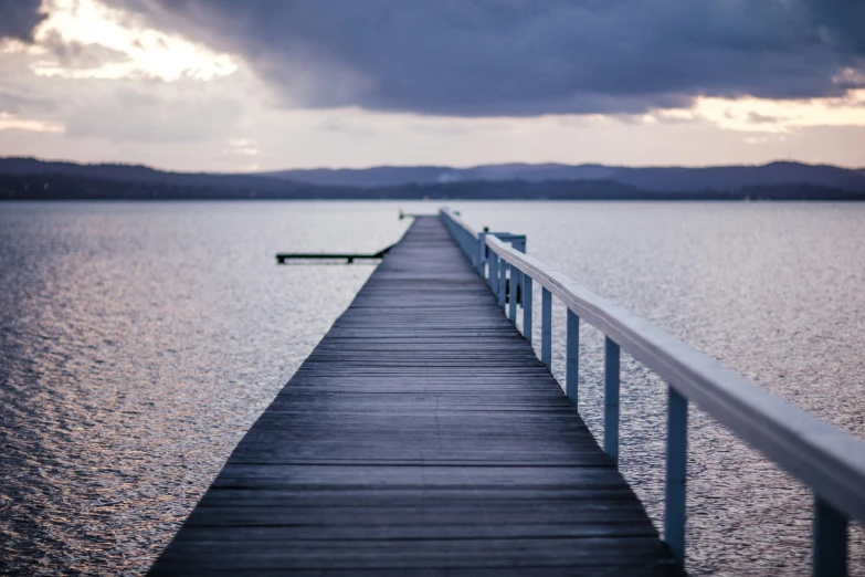 a pier with railing in foreground and clouds