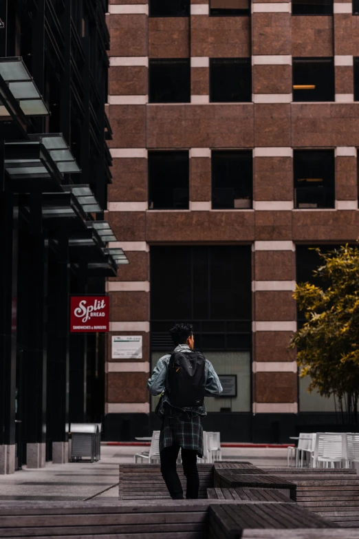 a man walks past a building that is tall with windows