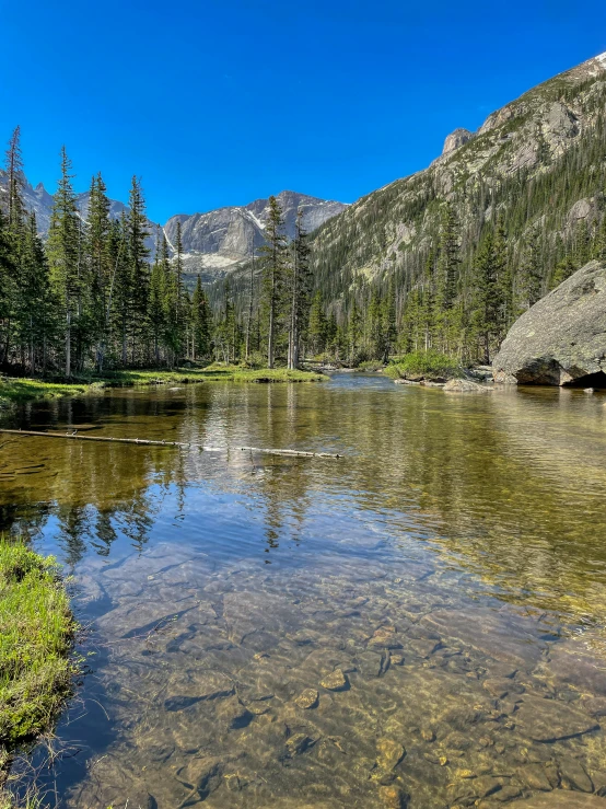 some small pond surrounded by trees and some mountain