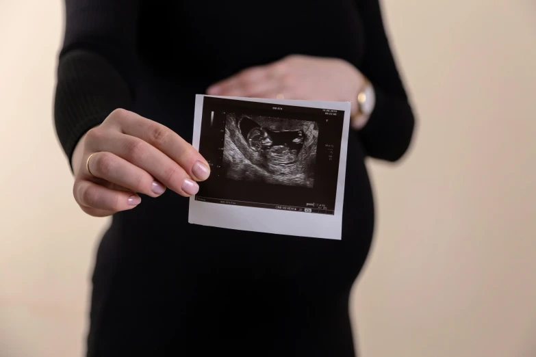 a pregnant woman holding up her picture showing an interesting hand gesture