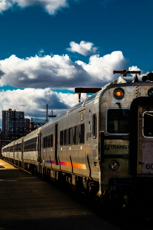 a train traveling past tall buildings on a cloudy day